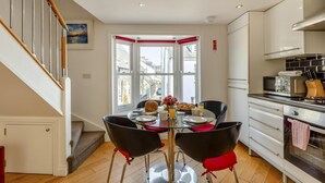 Een moderne keuken met een eethoek, een trap en uitzicht op de straat.