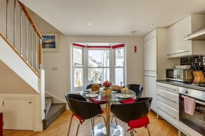 Eine moderne Küche mit Essbereich, einer Treppe und Blick auf die Straße.