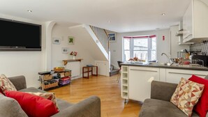 Een moderne woonkamer met een flatscreen televisie, grijze banken en een houten vloer.