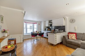 Une cuisine moderne avec des meubles blancs, un plan de travail noir et un coin repas comprenant une table et des chaises.