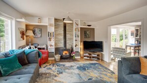 Un salon moderne doté d’une cheminée, d’un téléviseur et d’un coin salon confortable.