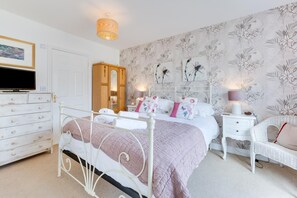 A bedroom with a bed, dresser, nightstand, and a wicker chair. - 5 Bed in nr Beadnell (oc-565945) (Beadnell)