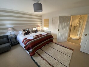 Une chambre d’hôtel avec un lit, des tables de chevet, une lampe, une douche et une porte.
