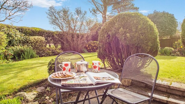 An outdoor seating area with a table set for tea, surrounded by well-maintained hedges and trees. - 2 Bed in Whitby (oc-w104) (Whitby)