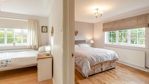 A bedroom with a bed, a bedside table, a lamp, a window with curtains, and a radiator. - 2 Bed in Whitby (oc-w104) (Whitby)