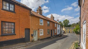 Een smalle straat met traditionele bakstenen huizen, een heldere lucht en een rustige woonwijk.