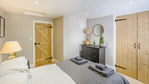 Een slaapkamer met een bed, nachtkastje, kaptafel, spiegel en een kledingkast.
