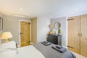 Ein Schlafzimmer mit Bett, Nachttisch, Kommode, Spiegel und Kleiderschrank.