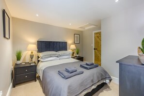 A neatly arranged bedroom with a bed, bedside tables, lamps, and a door. - 1 Bed in Woodbridge (oc-11ang) (Woodbridge)