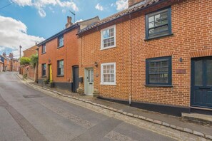 A row of red brick houses with white doors and windows, a clear sky, and a quiet street. - 1 Bed in Woodbridge (oc-11ang) (Woodbridge)