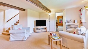 Ein Wohnzimmer mit Fernseher, zwei Sofas, einem Couchtisch und einer Treppe.