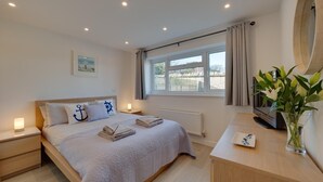 A neatly arranged bedroom with a bed, bedside tables, a TV, and a window with curtains. - 2 Bed in Swanage (oc-wy606) (Swanage)