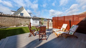 A deck with a table and two chairs, a stone wall, and a wooden fence. - 2 Bed in Swanage (oc-wy606) (Swanage)