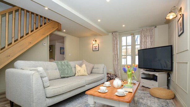 A living room with a grey sofa, wooden coffee table, and a TV on a stand. - 3 Bed in Petrockstow (oc-n33541) (Petrockstow)