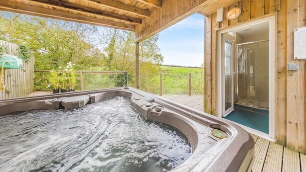 A wooden deck with a hot tub, a glass-enclosed shower, and a view of a green field. - 1 Bed in Moylegrove (oc-b33506) (Cardigan)