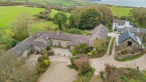 A rural property with stone buildings, a gravel driveway, and a view of the sea. - 1 Bed in Moylegrove (oc-b33506) (Cardigan)