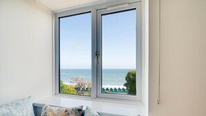 A room with a large window overlooking the sea, a white wall, and a colorful cushion on the window sill. - 2 Bed in Langland (oc-hh1005) (Newton)