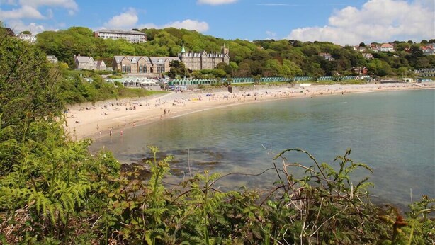 A coastal beach with a historic building and lush greenery. - 2 Bed in Langland (oc-hh1005) (Newton)