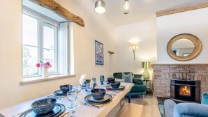 A dining area with a long table set for a meal, a fireplace, and a cozy seating arrangement. - 3 Bed in Moylegrove (oc-s33507) (Cardigan)