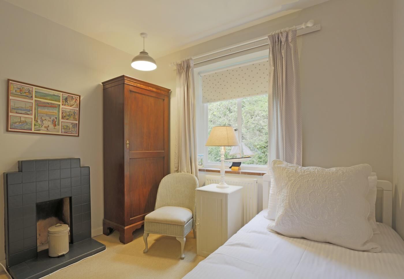 Quarto com cama, uma cadeira, guarda-roupa de madeira, lareira, janela com cortinas e luminária de parede.