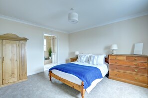 Une chambre à coucher avec un lit en bois, une commode en bois, une table de chevet et une armoire.