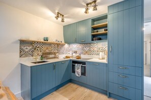 A kitchen with blue cabinets, a patterned backsplash, and a built-in oven.