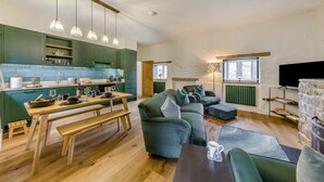 Eine moderne Küche mit grünen Schränken, einem Holztisch und Pendelleuchten.