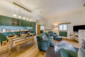 Eine moderne Küche mit grünen Schränken, einem Holztisch und Pendelleuchten.