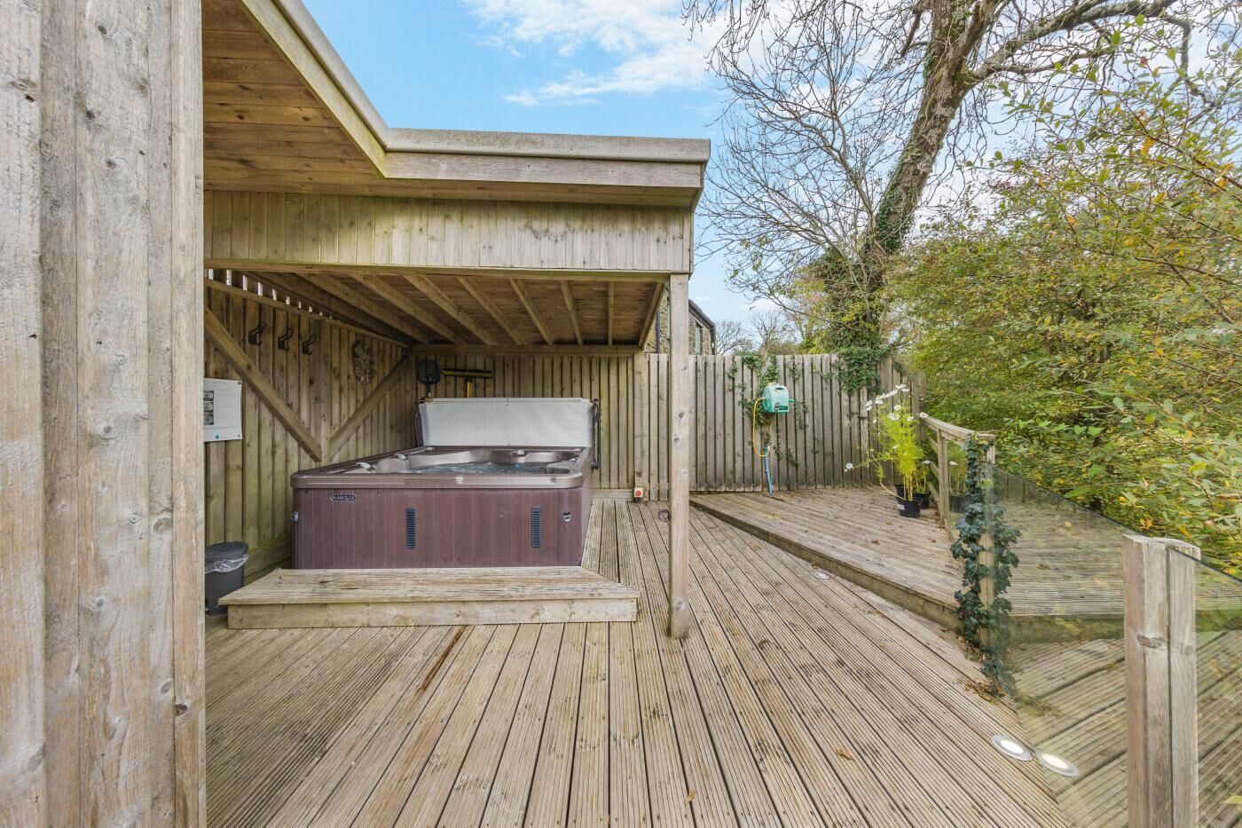 A wooden deck with a hot tub, a wooden fence, and a garden area.