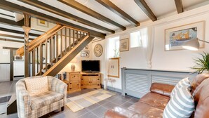 A spacious living room with a staircase, a television, a fireplace, and a couch. - 2 Bed in Penzance (oc-p00597) (Whitecross)