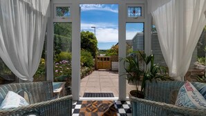 A conservatory with wicker furniture, a checkered mat, and a view of a garden and sky. - 2 Bed in Penzance (oc-p00597) (Whitecross)