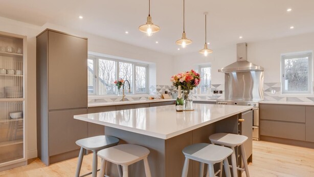 A modern kitchen with a large island, bar stools, pendant lights, and a view of the outside. - 4 Bed in Rock (oc-nb1952) (Rock)