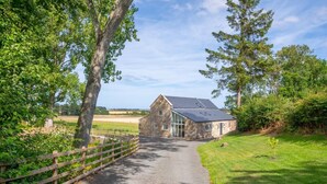 A stone building with a sloped roof, a paved driveway, and a wooden fence. - 4 Bed in Rock (oc-nb1952) (Rock)