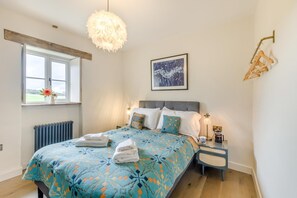 A bedroom with a bed, a window, a radiator, a bedside table with a lamp, and a wall-mounted coat rack. - 2 Bed in Moylegrove (oc-s33510) (Cardigan)