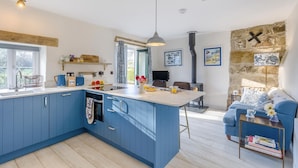 A modern kitchen with blue cabinets, a central island, and a stone wall.