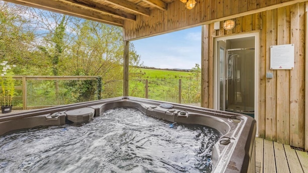 A wooden deck with a hot tub and a door to the right.