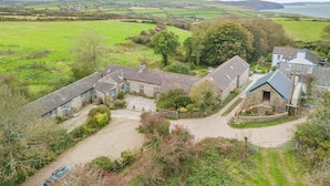 A rural property with stone buildings, a gravel driveway, and a view of the surrounding countryside and water body.