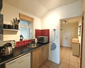 A compact kitchen with a toaster, kettle, and a dishwasher.
