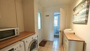 Une cuisine compacte équipée d’un four à micro-ondes, d’un lave-linge et d’un petit placard.