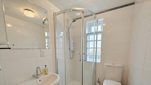 Une salle de bain avec une douche à parois de verre, un lavabo, des toilettes et un miroir.