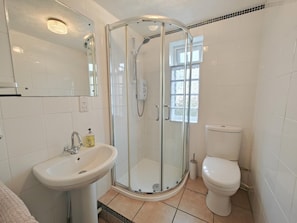 A bathroom with a glass-enclosed shower, a sink, a toilet, and a mirror.