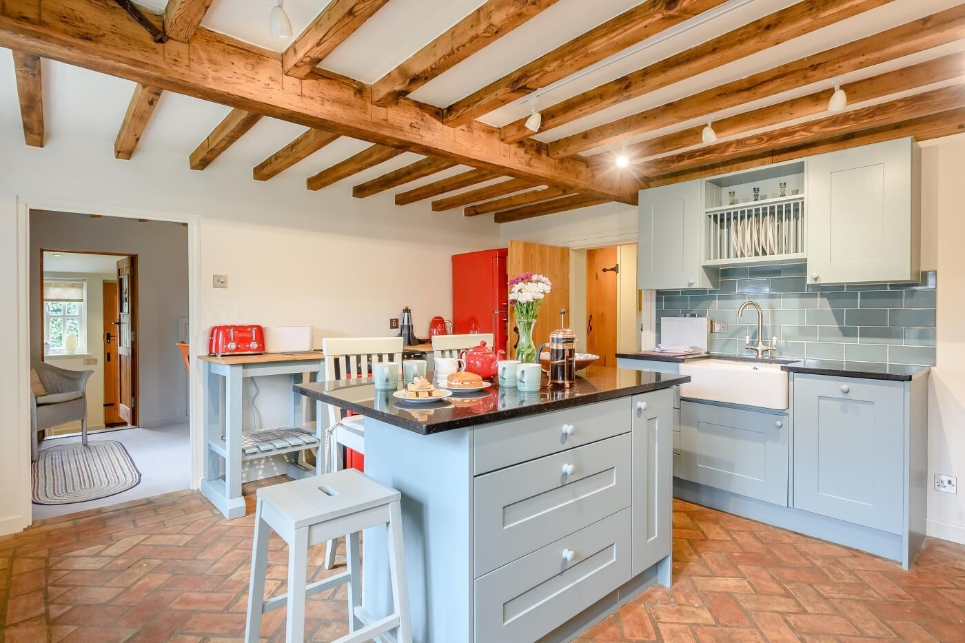 A modern kitchen with a central island, grey cabinets, and a wooden ceiling.
