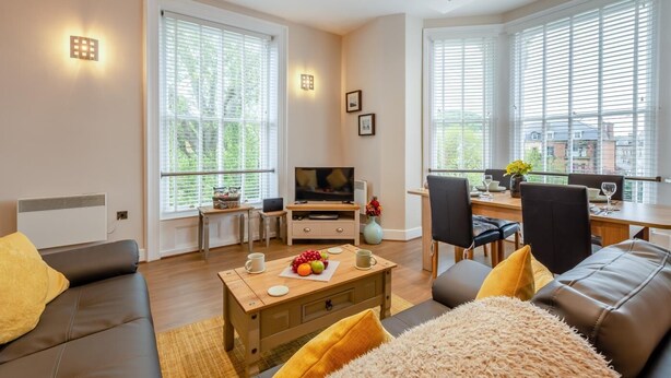 Ett modernt vardagsrum med en soffa, ett soffbord, en tv och en matplats med stolar och ett bord.