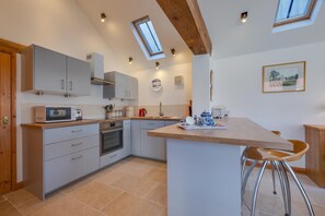 Eine moderne Küche mit Kochinsel, integrierten Geräten und einer schrägen Decke mit Dachfenstern.