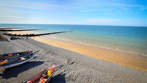 A beach with a pebble shore, a pier extending into the sea, and two boats on the sand. - 2 Bed in Holt (oc-2231) (Holt)