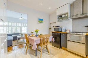 Eine moderne Küche mit Essbereich, inklusive Holztisch, Stühlen, Kühlschrank, Herd und Mikrowelle.