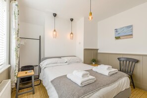 Ein Hotelzimmer mit Bett, Nachttisch, Stuhl und einem Bild an der Wand.