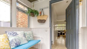 A room with a blue sofa, a hanging plant, and a door leading to another space. - 2 Bed in Holt (oc-2231) (Holt)