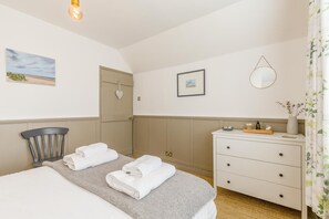 Une chambre d’hôtel comprenant un lit, une table de chevet, une chaise, une armoire, un miroir et un tableau accroché au mur.