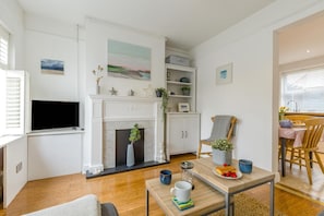 A living room with a fireplace, a television, and a dining area with a table set for two.